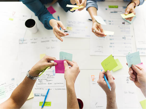 Workshop-Situation: Hände mit Haftnotizen über Tisch